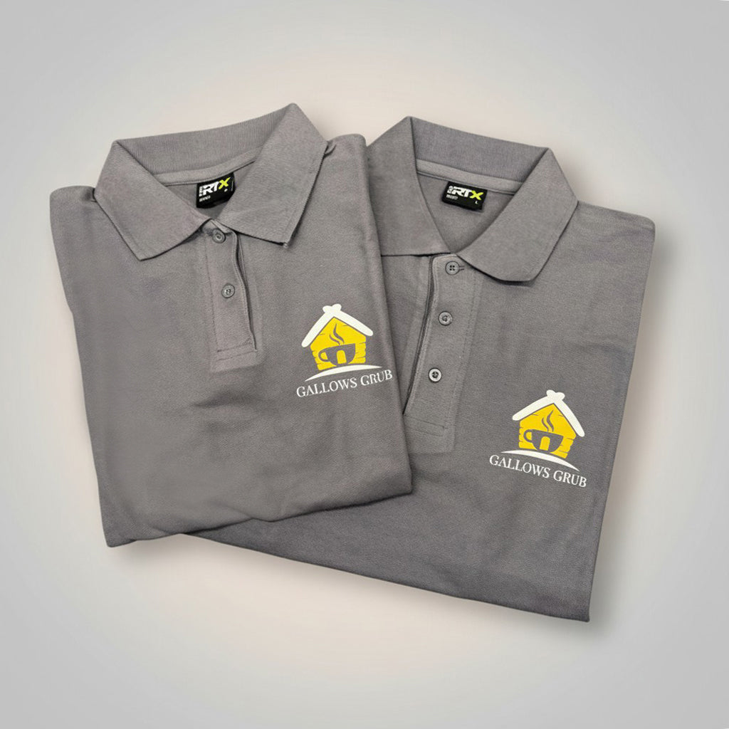 Two folded grey polo shirts with an Ilkeston based Gallows Grub logo on a light grey background